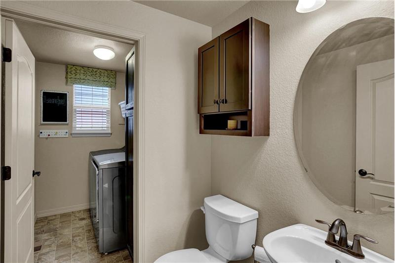 Convenient main-level Powder Bathroom and Laundry Room with window, cabinet, and shelves