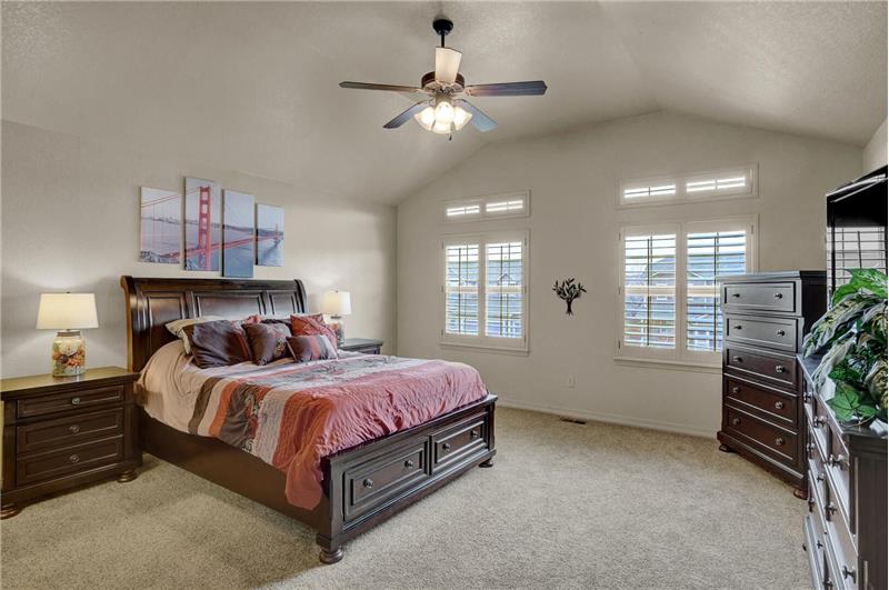 Upper-level vaulted Master Bedroom with neutral carpet, lighted ceiling fan, and plantation shutters