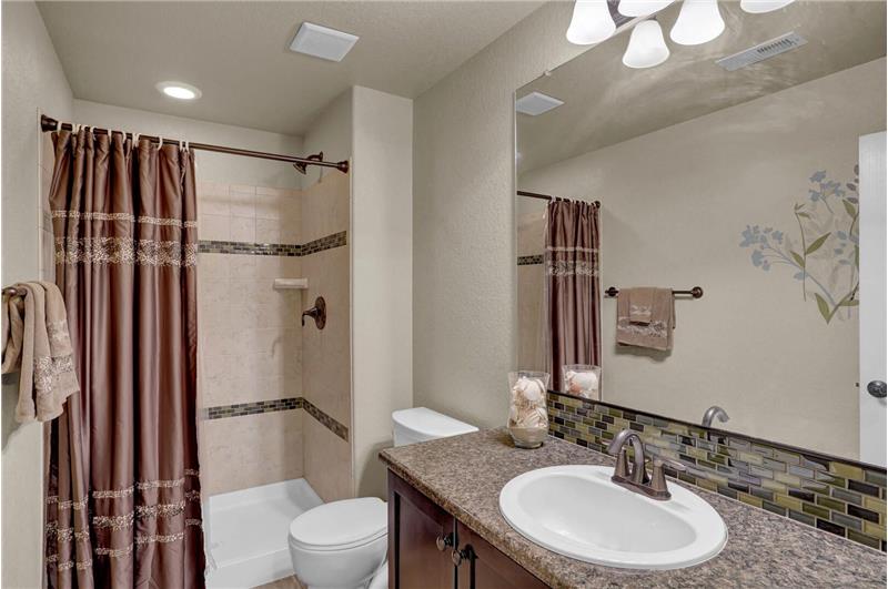Basement Shower Bathroom with vanity and tiled shower