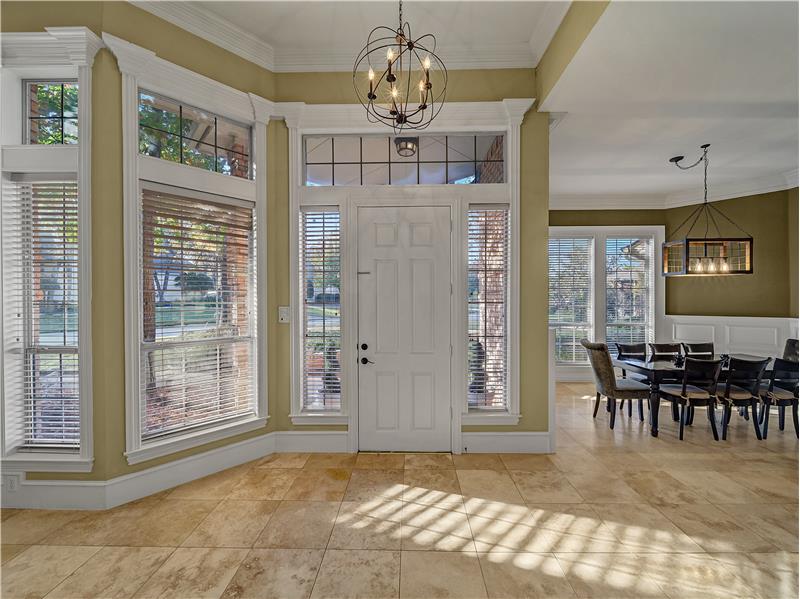 Elegant entryway with lots of sunlight, ornamental molding, and a beautiful chandelier