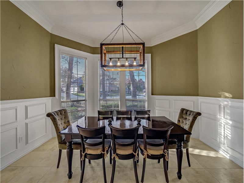 Tiled dining room with ornamental molding and beautiful updated decorative lighting.