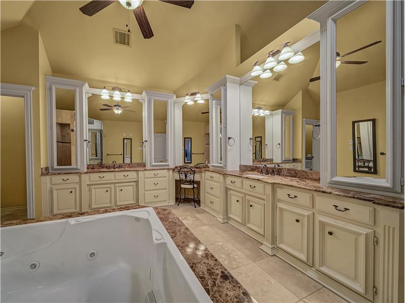 Primary Bathroom with storage galore! Jetted tub, vanity, and dual sinks.