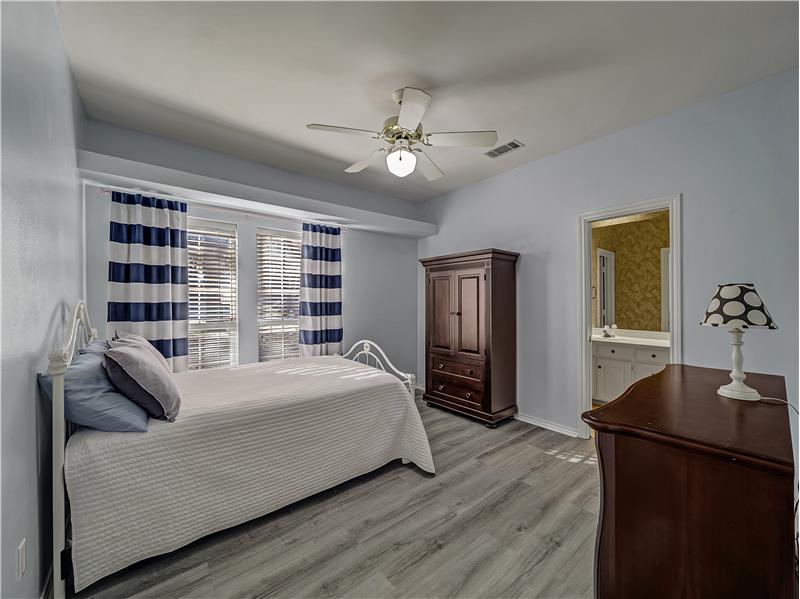 Secondary Bedroom with ceiling fan, light wood flooring, and ensuite bathroom!