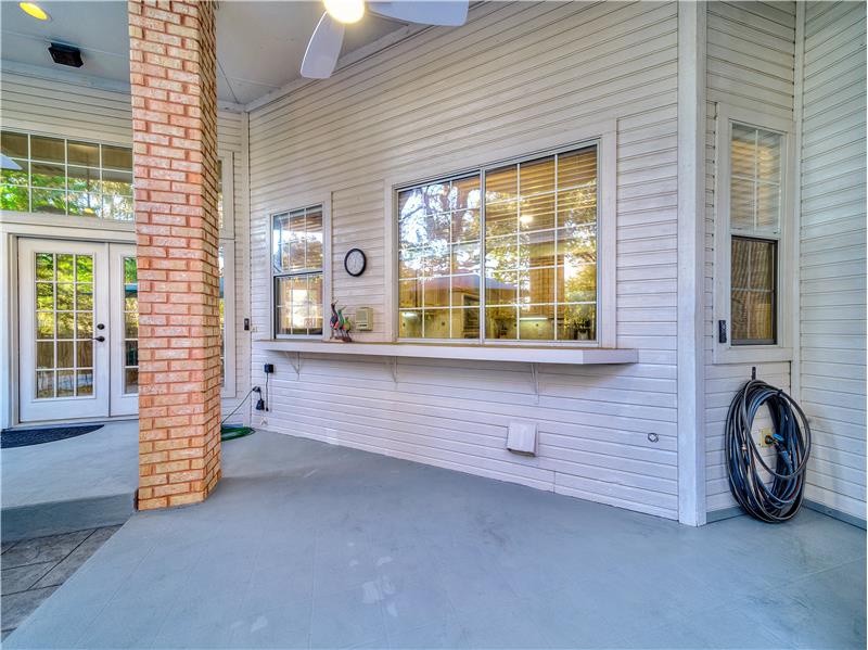 View of covered patio featuring ceiling fan and serving bar!