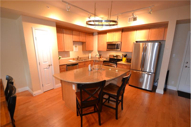 Kitchen with slab granite counters, island with breakfast bar, stainless steel appliances and pantry