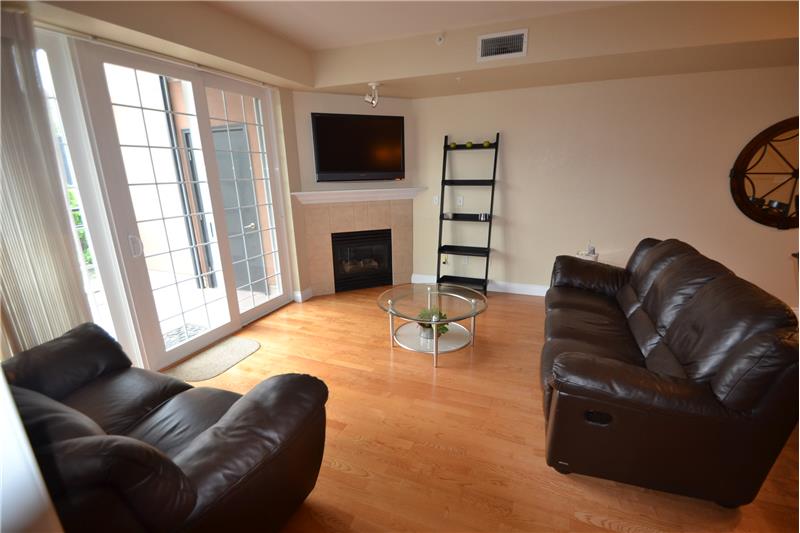 Living room has gas fireplace and wall-mounted TV, plus door to patio