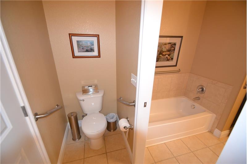 Toilet in half bathroom with master bathroom tub visible through open pocket door
