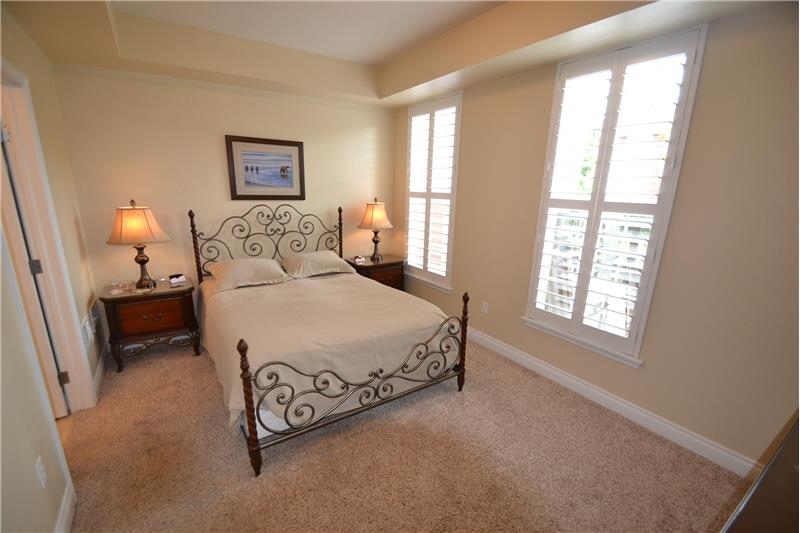 Master bedroom has plantation shutters overlooking patio and Clear Creek