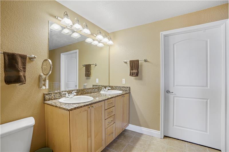 Master bathroom showing double vanity and door to walk-in closet