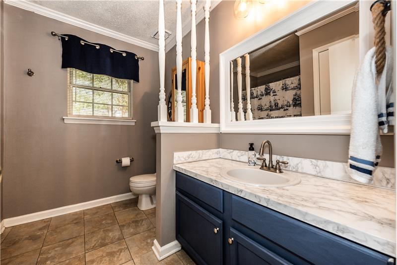 Master bath has access doors to owner's suite and the hallway. Decorative half-wall separates vanity from commode.