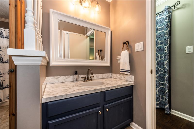 Master bath with updated light fixture, framed mirror, cabinet vanity with storage below and updated faucet.
