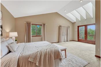 The expansive primary suite has skylights & French doors that open to a private balcony overlooking the mountains & Pikes Peak.