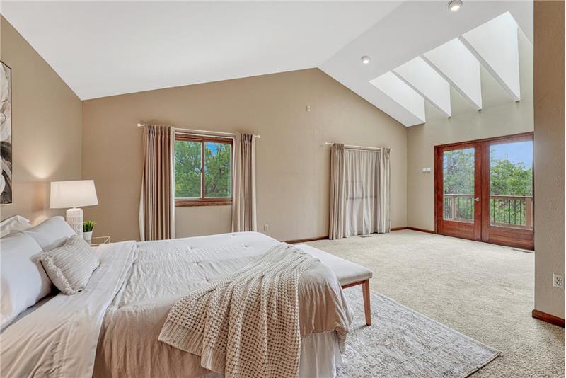 The expansive primary suite has skylights & French doors that open to a private balcony overlooking the mountains & Pikes Peak.