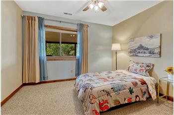 Main level Bedroom with lighted ceiling fan and neutral carpet.
