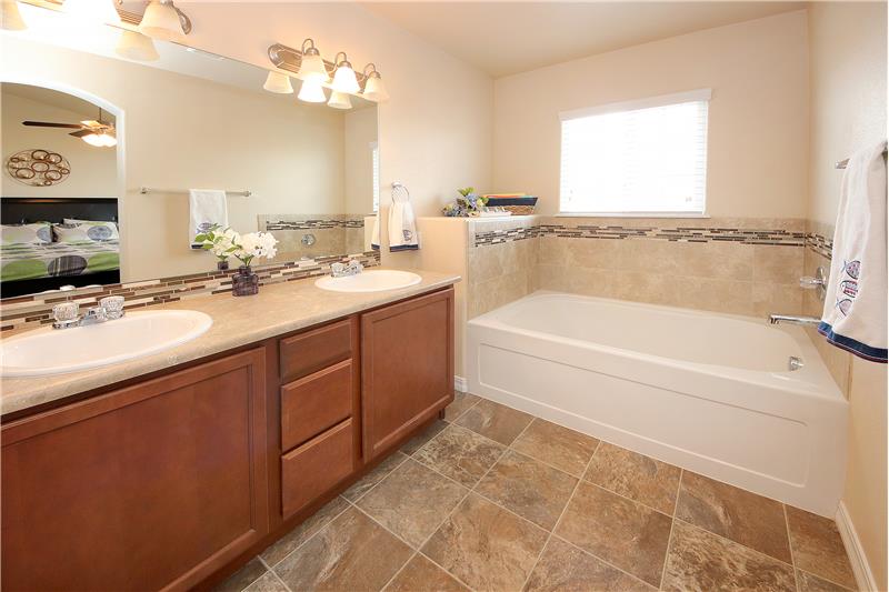 Master bathroom with double sinks, soaking tub, and large shower