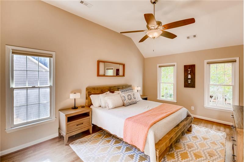 Serene and spacious master suite with vaulted ceiling, hardwood floors.