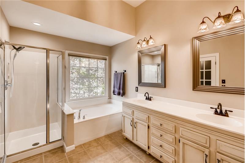 Updated master bathroom features tile floors, soaking tub, separate shower, double sink vanity with custom cabinets.