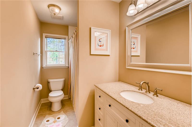 Fully renovated, hall bath features new vanity, new tile flooring, new tub-shower, new lighting, new fixtures and toilet.