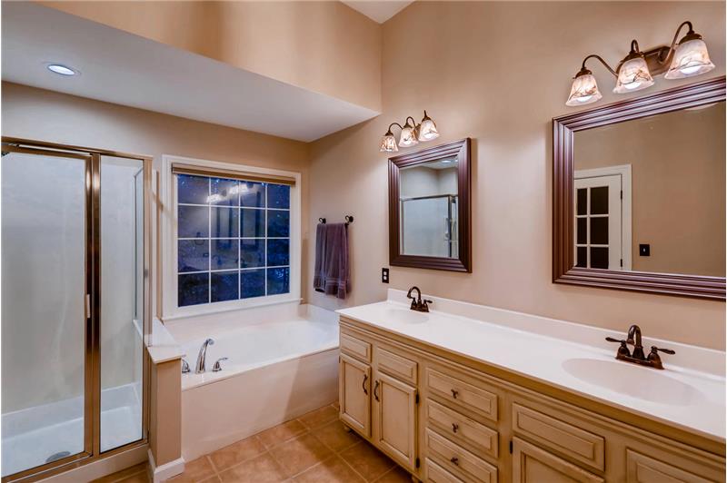 En-suite master bathroom accessed via a custom barn-style door, vaulted ceiling, updated mirrors and light fixtures.