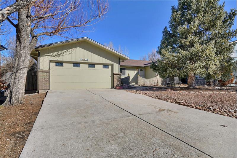 Long driveway and low maintenance front yard with mature trees and brick enclosed front front walkway to covered entry.