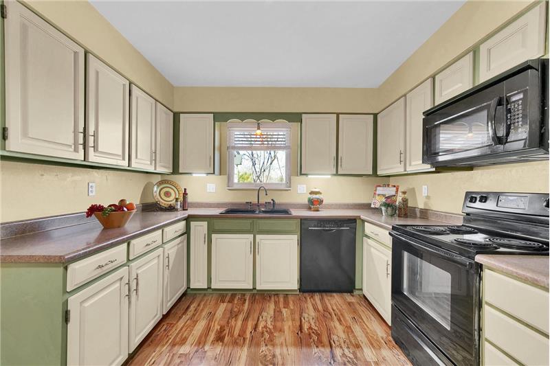 The  eat-in Kitchen features hickory laminate flooring, painted cabinets with Formica countertops, and black appliances.
