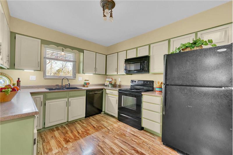Black appliances include a smooth top range oven, dishwasher, and built-in microwave oven. 