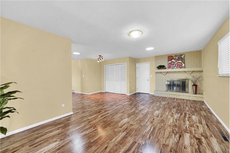 Huge, open Family Room with installed solar tubes and a wood burning fireplace with raised hearth, mantle, and brick surround.