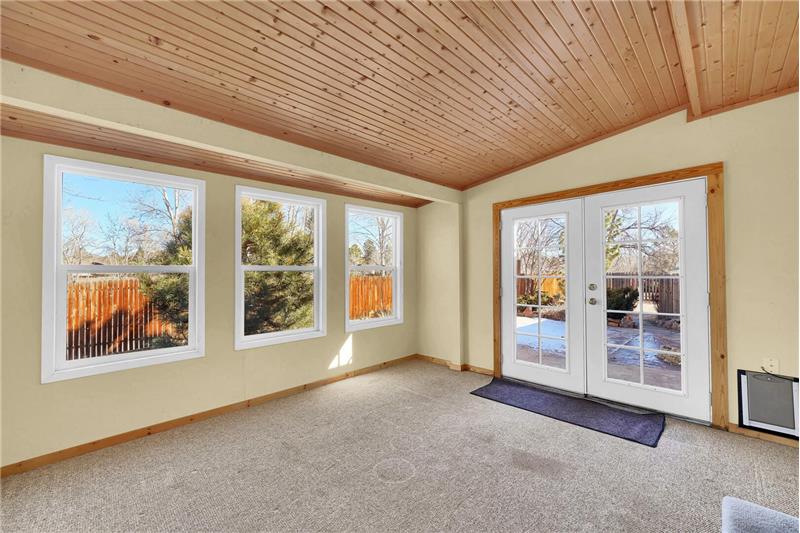 The heated Sunroom includes a wood paneled ceiling, wall of vinyl windows, and walk-out to the backyard.