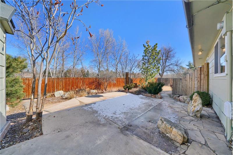 Fenced backyard with auto sprinklers, a flagstone patio and mature trees and shrubs.