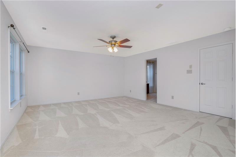 Owner's suite features lots of natural light, ceiling fan with light, en-suite bathroom.