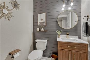 Convenient main level Powder Bathroom with vanity, round mirror, and attractive accent wall.