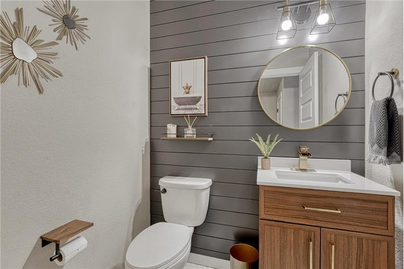 Convenient main level Powder Bathroom with vanity, round mirror, and attractive accent wall.