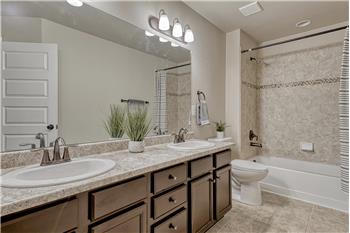 Upper Level Full Bathroom with dual sink vanity, mirror, and tiled tub/shower.