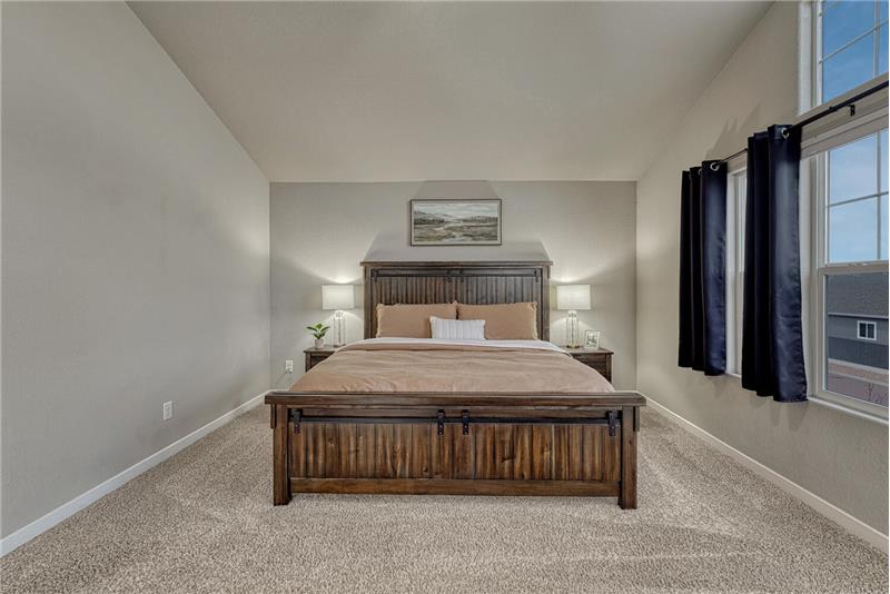 The upper level Primary Bedroom is a private retreat offering neutral carpet, high ceilings and a wall of windows.