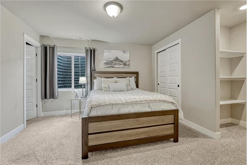 Basement Bedroom with neutral carpet, built-in shelves, and adjoining Full Bathroom.