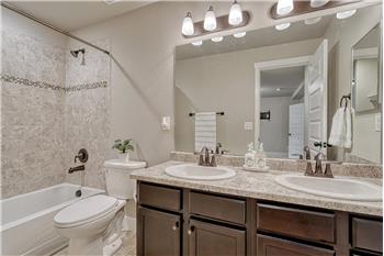 Basement Full Bathroom with dual sink vanity, mirror, and tiled tub/shower.