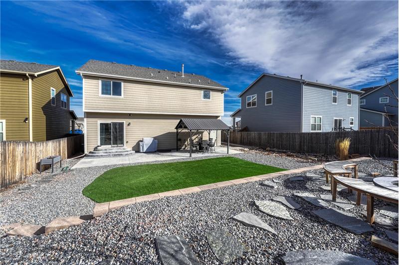 Fenced backyard with rock gardens and grass area for the kids and pets to play and fire pit with bench seats.