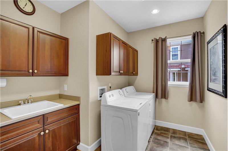The Laundry Rm has tile floors, cabinets, a sink, & garage access. Washer/Dryer stay