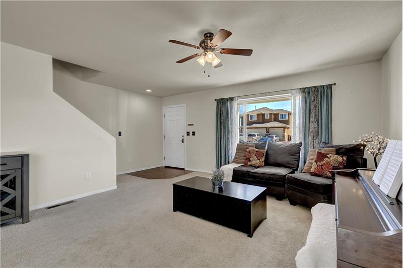 Wood laminate floor entry into the Formal Living Room with lighted ceiling fan, neutral carpet, & large window