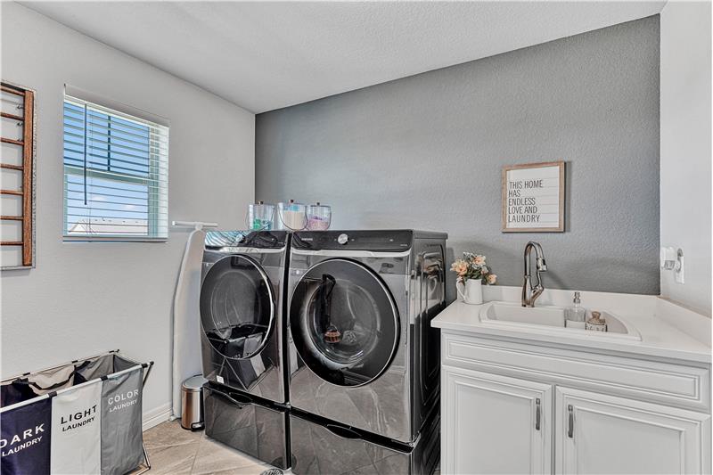 Large laundry room tile flooring, sink, and window!