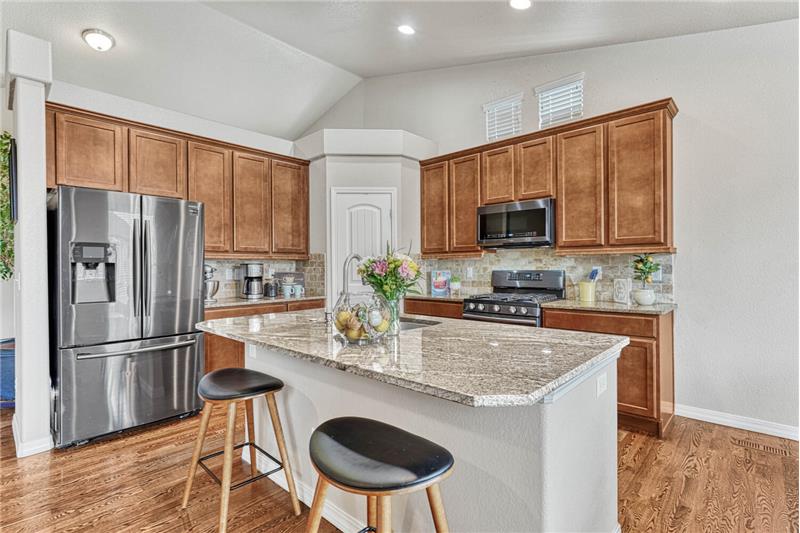 Functional kitchen with a pantry, granite counters, a stone tile backsplash, gas range oven w/double ovens, overhead microwave,