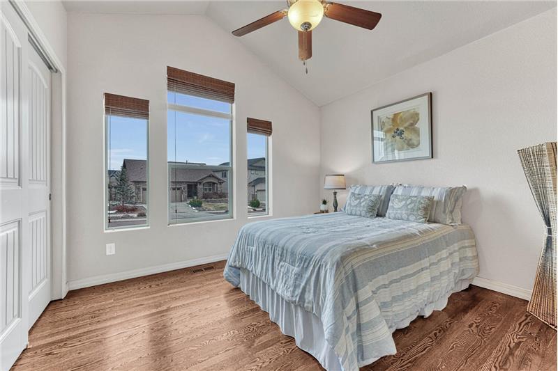 Secondary bedroom on main level with hardwood flooring and a ceiling fan