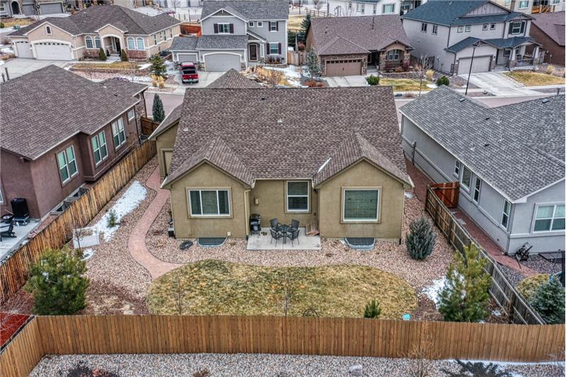 Fully landscaped backyard with a patio, trees, perennials, planter box, and a rock walkway to the front.