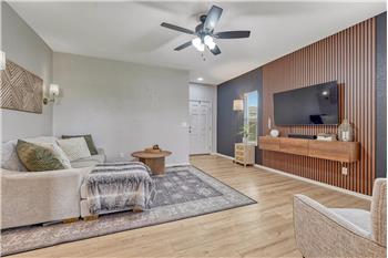 The spacious living room blends warmth and contemporary style with wood accents, and a sleek feature wall with floating console.