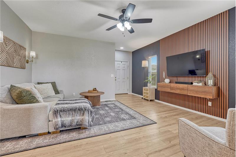 The spacious living room blends warmth and contemporary style with wood accents, and a sleek feature wall with floating console.