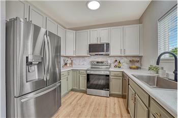 The kitchen is inviting and practical, offering ample wood cabinetry, Formica countertops, tile backsplash, and SS appliances.