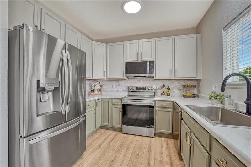 The kitchen is inviting and practical, offering ample wood cabinetry, Formica countertops, tile backsplash, and SS appliances.
