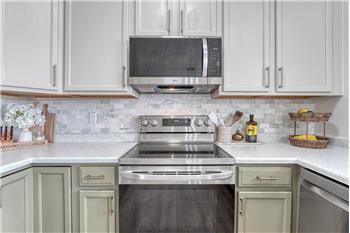Beautifully tiled backsplash, painted wood cabinets, and solid surface countertops.