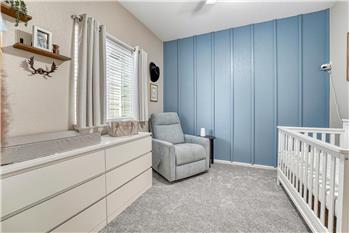 Main Level Bedroom #2 with neutral carpet, lighted ceiling fan, and accent wall with designer paint tone.