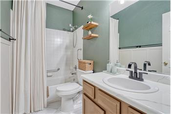 The Primary Bathroom features tile flooring, a vanity, mirror, and tiled tub/shower.